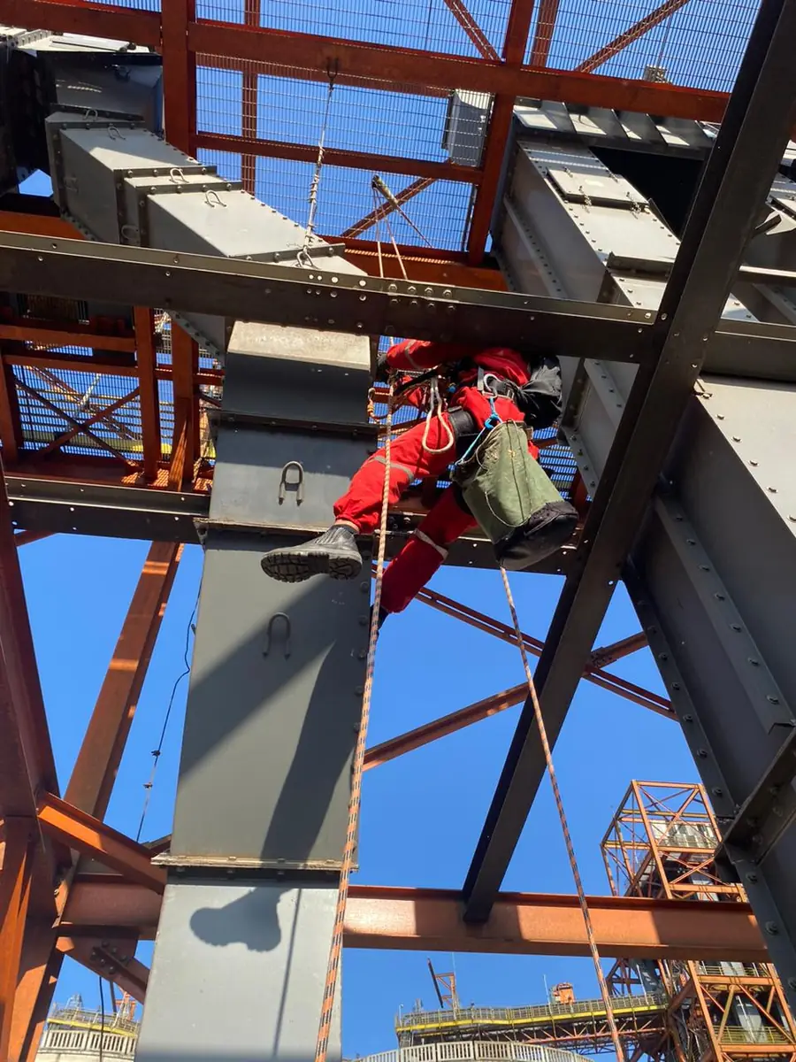 Alpinista em estrutura metálica industrial