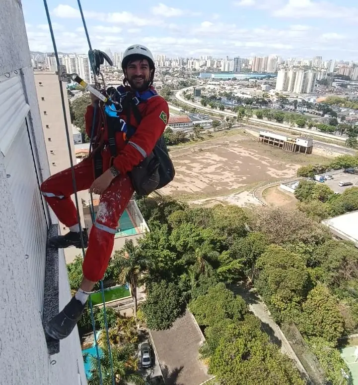 Alpinista industrial em fachada com vista da cidade